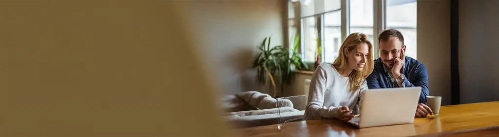 Ein Paar informiert sich am Laptop darüber, was ein Tagesgeldkonto ist.